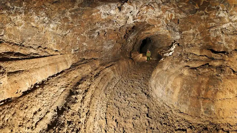 "Vista del interior de la Cueva del Viento en Tenerife, una de las cuevas volcánicas más extensas de Europa. La imagen muestra un paisaje subterráneo con formaciones de lava, estalactitas y estalagmitas, y un sendero iluminado que permite a los visitantes explorar el impresionante laberinto de tubos volcánicos."