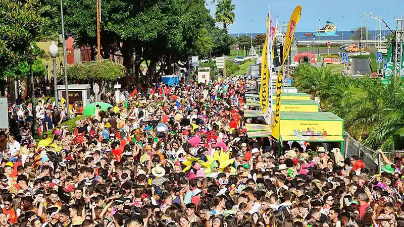 "Vista colorida del Carnaval de Las Palmas de Gran Canaria con un grupo de personas disfrazadas y disfrutando del ambiente festivo. Los disfraces son variados y llamativos, reflejando la alegría y el espíritu vibrante del evento."