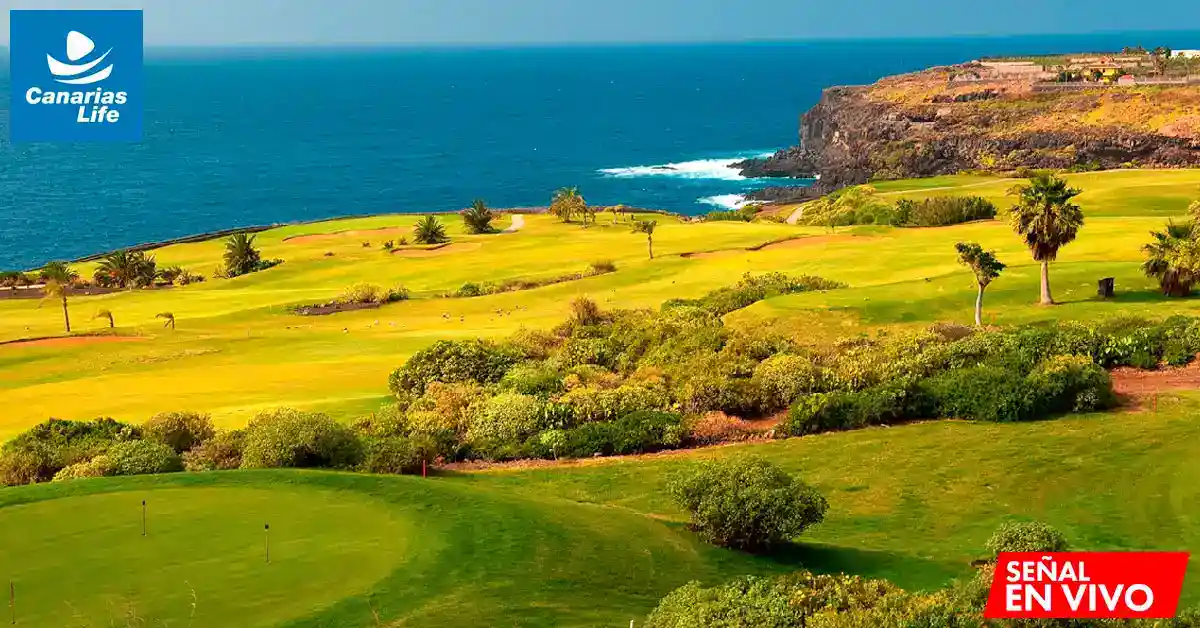 Paisaje costero con campo de golf, mar azul y vegetación verde, en una zona turística de Canarias.