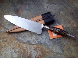 Mano sosteniendo una cuchilla antigua con mango decorado, probablemente de uso doméstico o ceremonial.