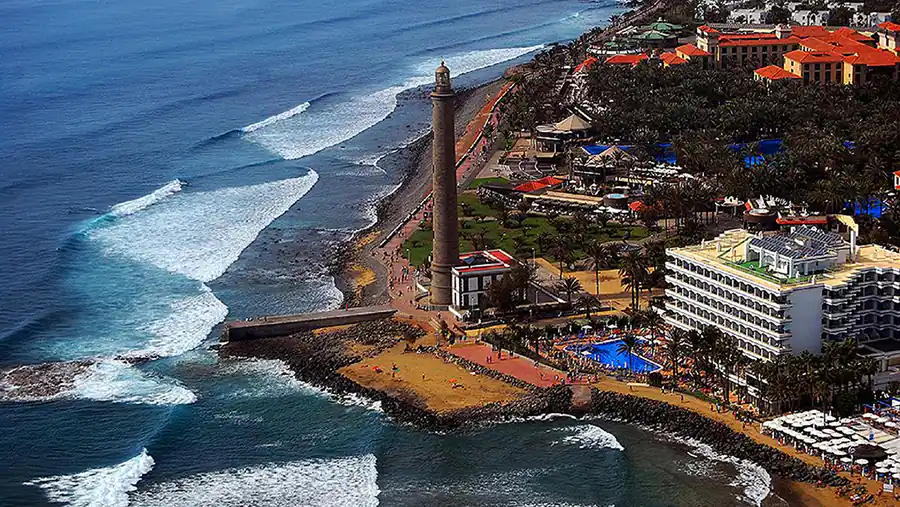 Faro de Maspalomas, Gran Canaria, con playas y hoteles rodeados de vegetación costera.