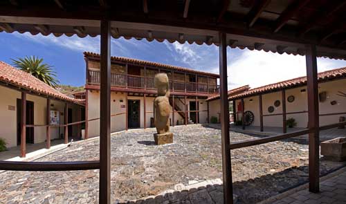 "Fachada del Museo Casa del Capitán en Canarias, con una entrada de madera y un carro antiguo en primer plano."