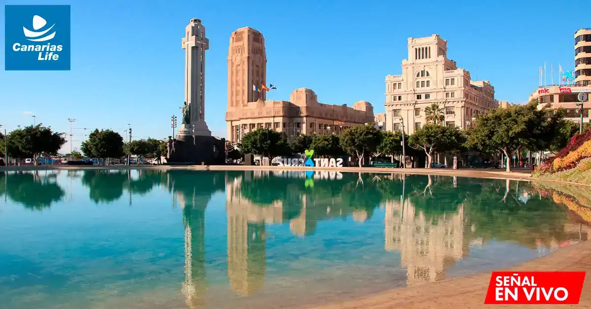 Plaza con monumento, edificios históricos, reflejo en el agua, paisaje urbano, Canarias Life logo.
