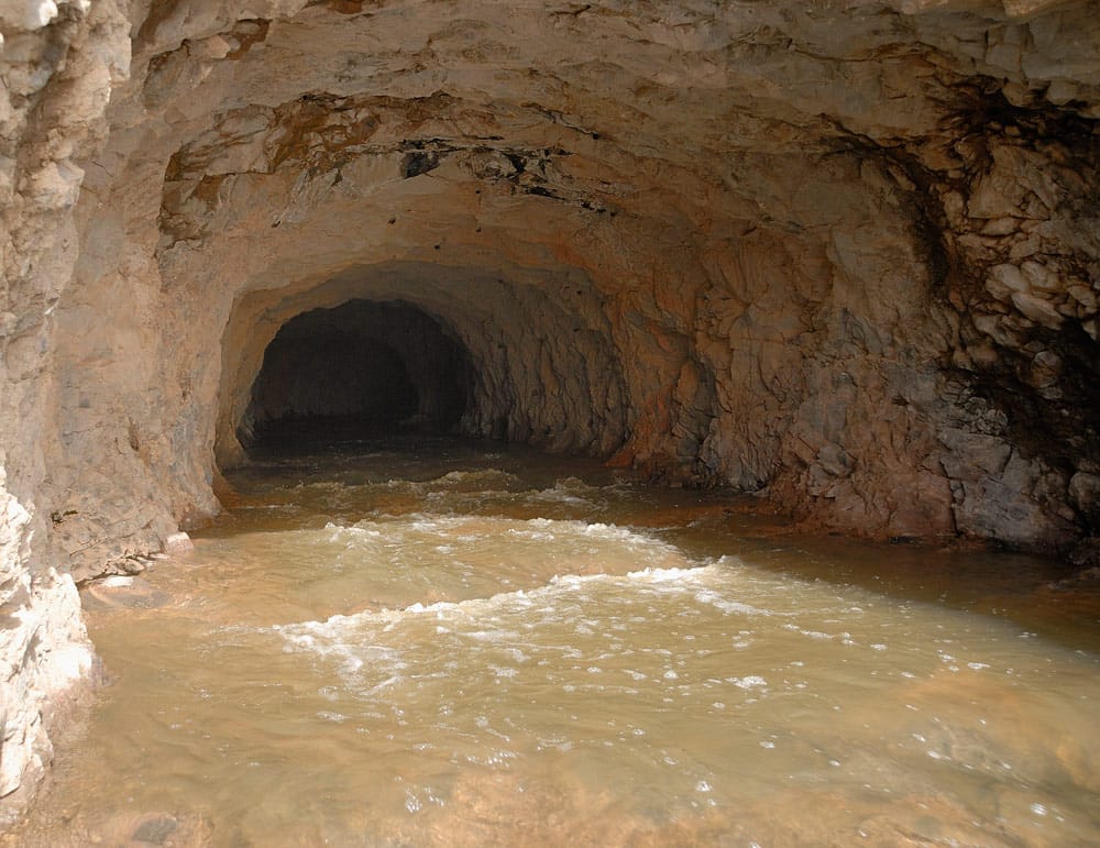 Túneles antiguos construidos con piedras, probablemente utilizados para almacenamiento o defensa, se observan desde una perspectiva lateral y frontal.