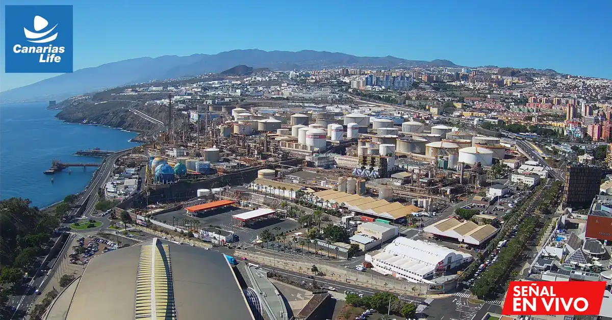 Vista nord de la ciudada de Santa Cruz a una ciudad costera, refinería petrolífera, y montañas en el horizonte.