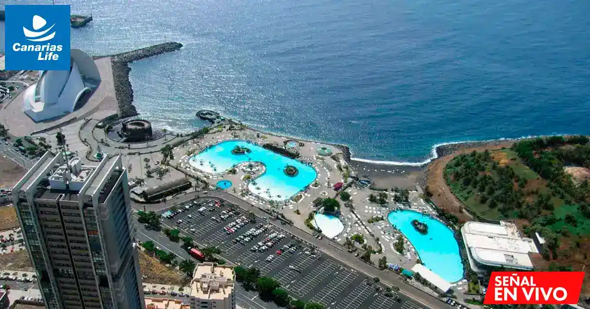 Vista aérea de una zona costera de arquitectura moderna, que incluye el emblemático Auditorio de Tenerife y las piscinas adyacentes, con el océano como telón de fondo.