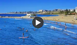 Playa con arena blanca, agua azul y sombrillas rojas en Playa del Inglés
