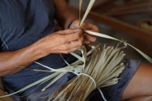 Uomo che lavora con palha, realizzando un oggetto manualmente, con mani esperte che manipolano la materia prima.