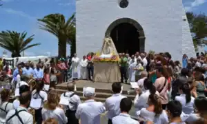 Festa religiosa con statua della Vergine, musica e congregazione in una chiesa bianca.