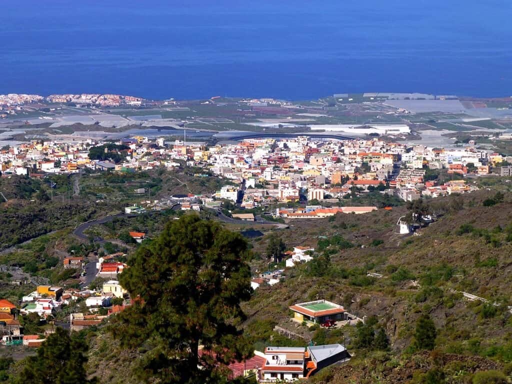 Pueblo costero con urbanización, campos y bosque cercano al mar.