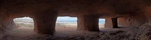 Interno della grotta con finestre che mostrano una vista panoramica del paesaggio costiero.