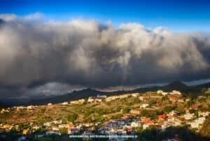 Nubes densas cubriendo una aldea canaria, con claros resaltando edificios y vegetación.