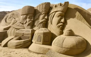 - Esculturas de arena con caras detalladas y elementos históricos en playa de Canarias.