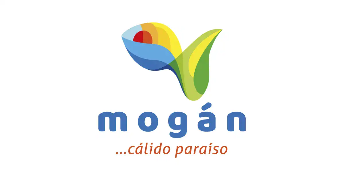 Logotipo de Mogán, "cálido paraíso", con una flor colorida y la palabra "Mogán" en azul, representando la belleza natural del lugar.