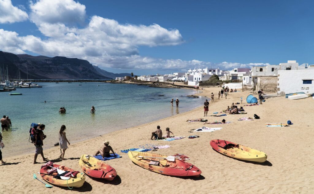 Aguas turquesas del puerto de Caleta del Sebo con embarcaciones y el paseo marítimo, La Graciosa, Lanzarote