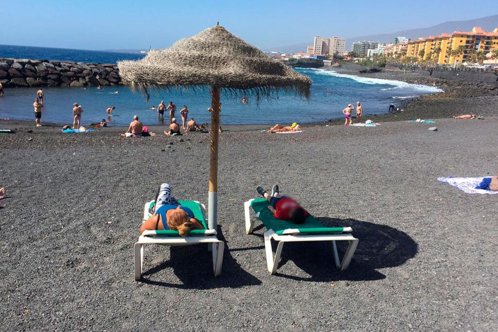 Bañistas en la Playa de Punta Larga con callaos y arena negra volcánica, Candelaria, Tenerife