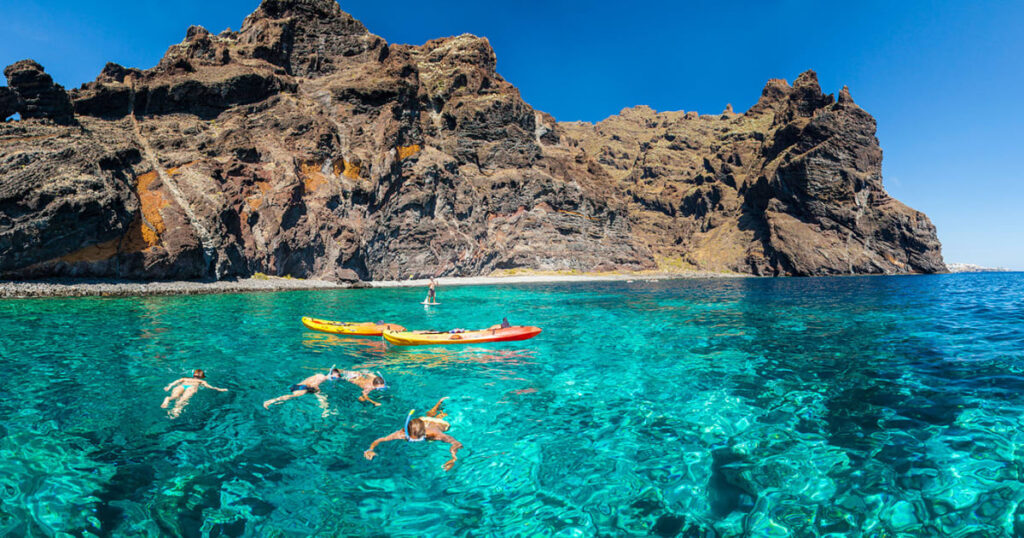 Kayak y actividades acuáticas en la Playa de Los GuÃos con los acantilados de Los Gigantes al fondo, Tenerife