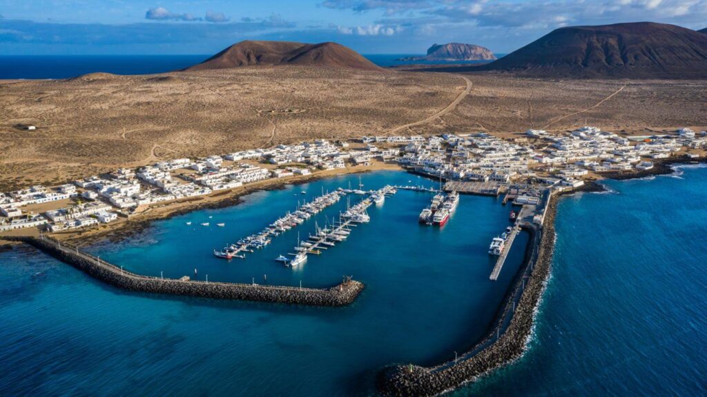 Puerto y marina de Caleta del Sebo con barcas amarradas y los acantilados de Famara al fondo, La Graciosa