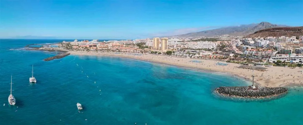 Arena dorada de la Playa Las Vistas en Los Cristianos Tenerife con fuente y barcos al fondo Arona