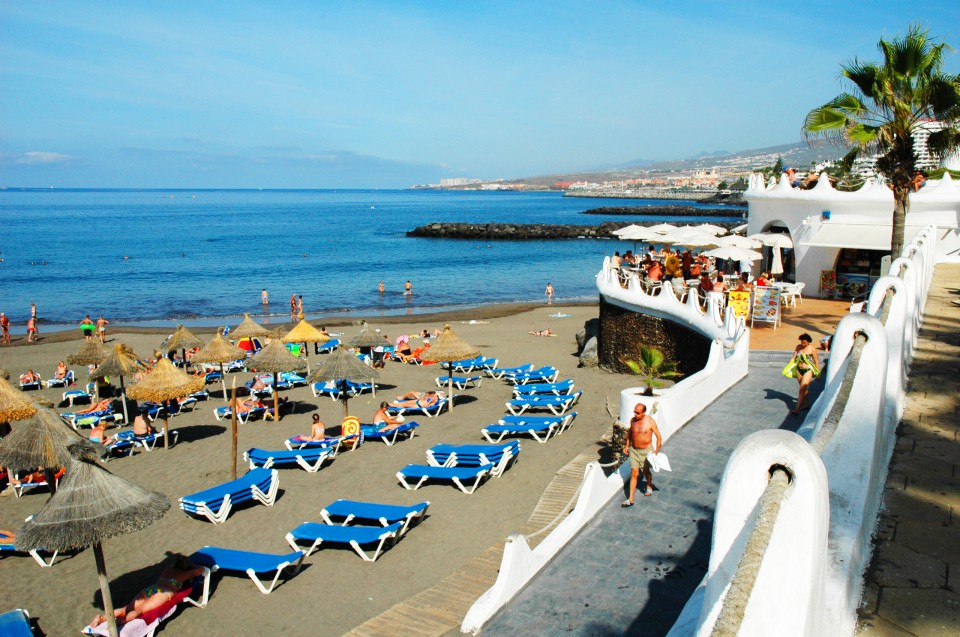 Arena dorada de la playa de Troya Tenerife con el paseo marítimo de Costa Adeje al fondo