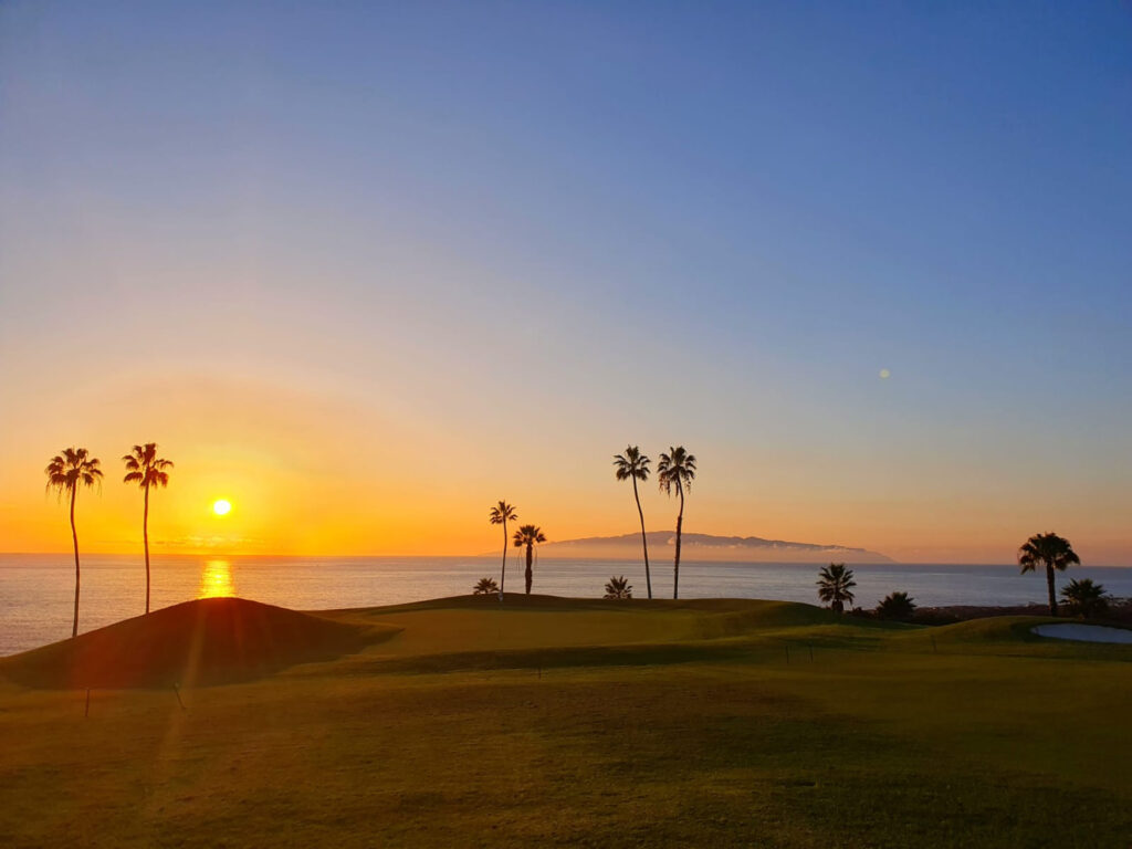 Atardecer en el Golf Costa Adeje con la isla de La Gomera al fondo y el campo iluminado, Tenerife