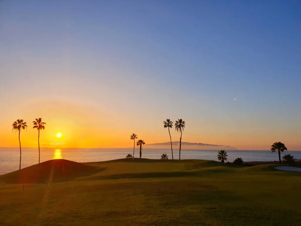 Tramonto al Golf Costa Adeje con l'isola di La Gomera sullo sfondo e il campo illuminato, Tenerife
