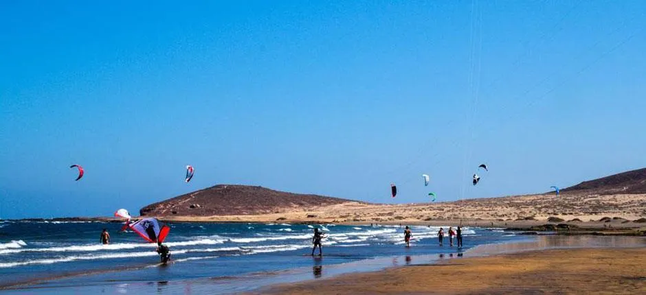 Kitesurfistas en la playa de El Médano con viento alisio y Montaña Roja al fondo