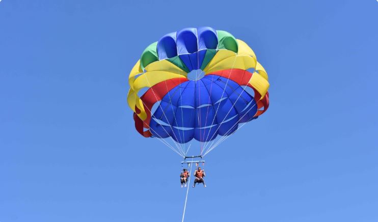 Parasailing al atardecer sobre la bahía de Taurito, playa con deportes acuáticos en Mogán