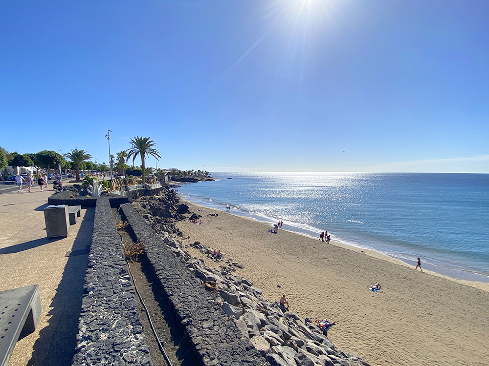 Playa Grande Puerto del Carmen Lanzarote con bañistas y paseo marítimo en la Avenida de las Playas