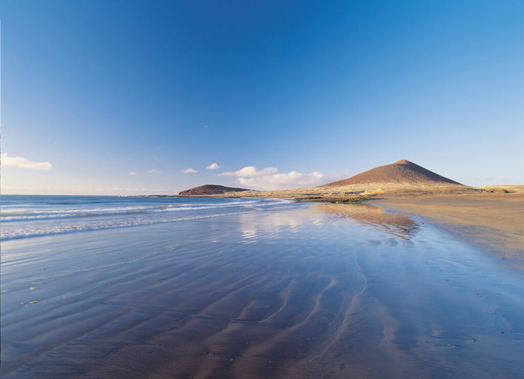 Playa Grande en El Médano con arena dorada y Montaña Roja al fondo en Tenerife