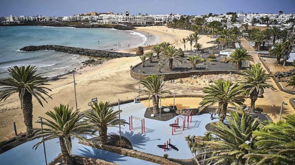 Playa Las Cucharas Costa Teguise Lanzarote con bañistas, paseo marítimo y el Atlántico al fondo