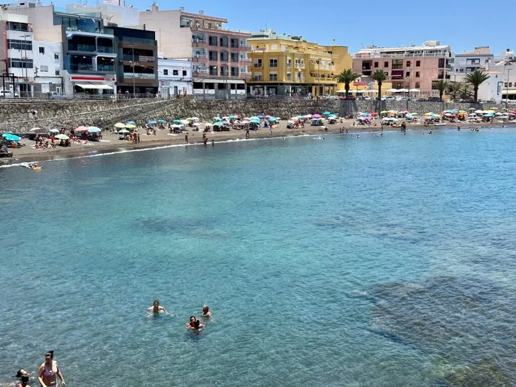 Playa Las Marañuelas Mogán con arena volcánica y puerto pesquero de Arguineguín, Gran Canaria