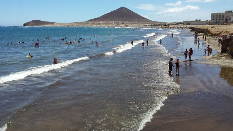 Playa Leocadio Machado en El Médano con surfistas y Montaña Roja al fondo, Tenerife