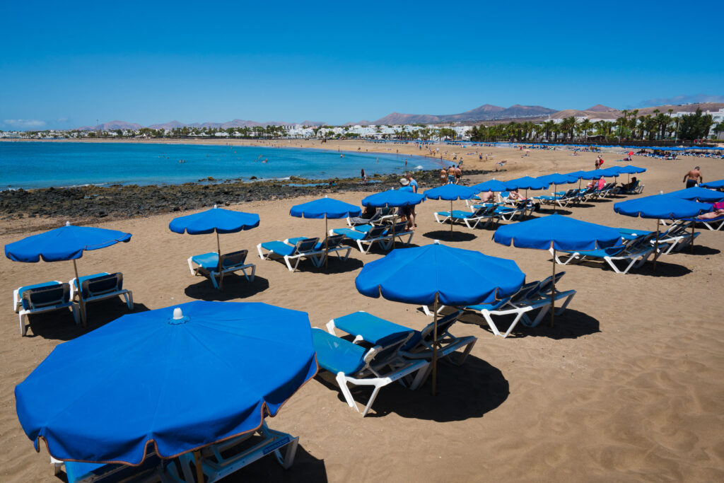 Playa Los Pocillos Puerto del Carmen Lanzarote con windsurfers y paseo marítimo al fondo