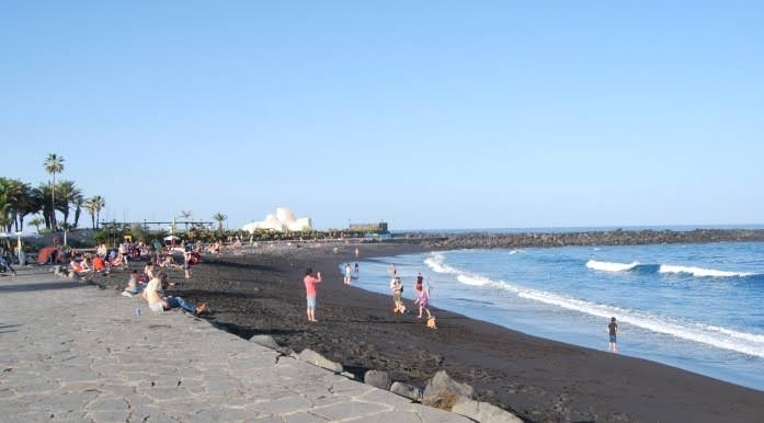 Playa Martiánez Puerto de la Cruz con arena negra volcánica y olas atlánticas en Tenerife norte