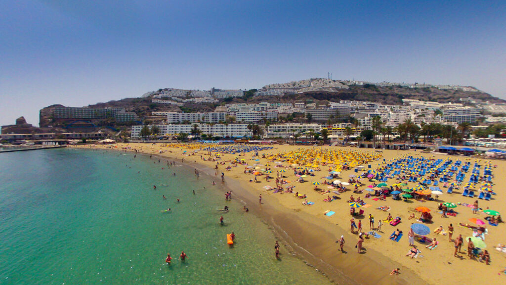 Playa de Puerto Rico Gran Canaria con arena dorada y aguas turquesas en calma, paseo marítimo y puerto deportivo, Mogán