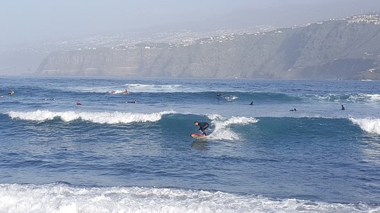 Surfistas en la Playa Martiánez Puerto de la Cruz con arena volcánica negra en Tenerife