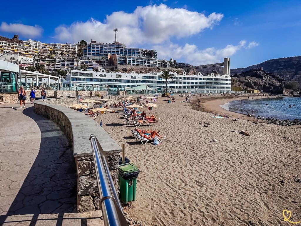 Vista de la playa del Cura en Mogán desde el paseo con acantilados volcánicos al fondo, Gran Canaria