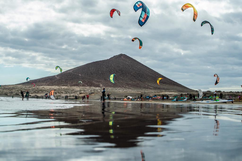 Vista de la zona de kitesurf de El Médano desde la orilla con cometas de colores y viento alisio, Tenerife